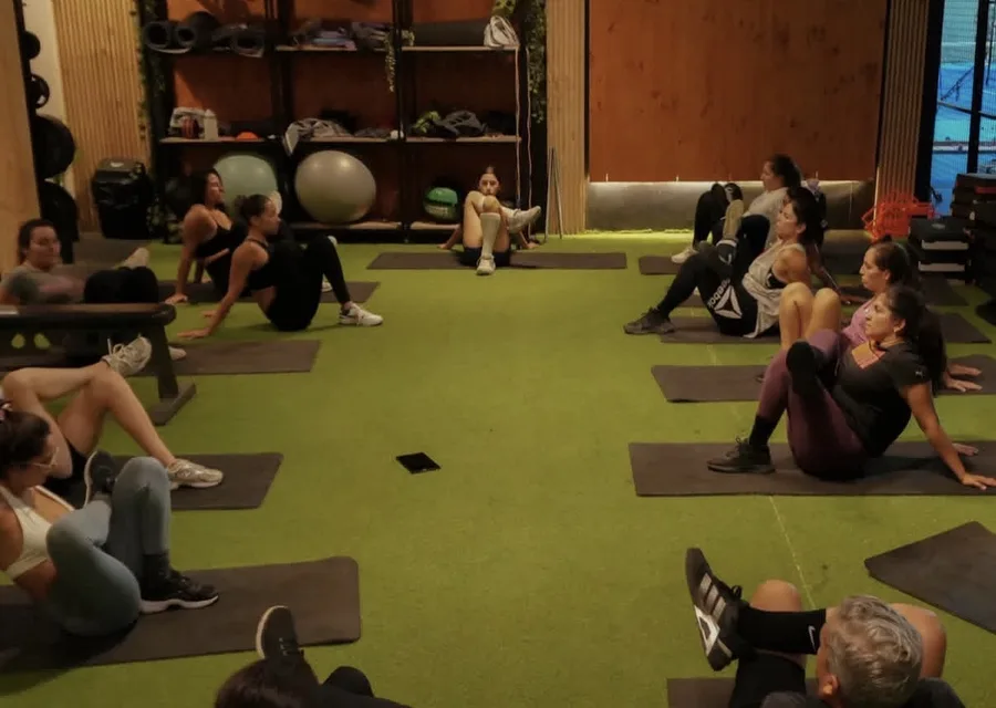 Clase grupal ejercitando abdominales en círculo sobre el turf