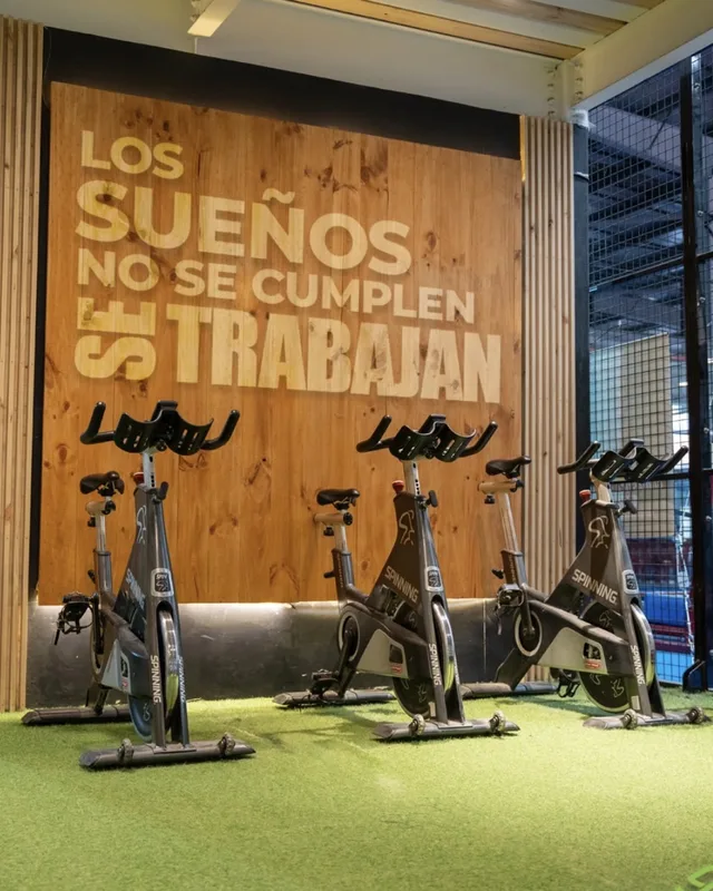Bicicletas de spinning frente al mural de madera «Los sueños no se cumplen, se trabajan»