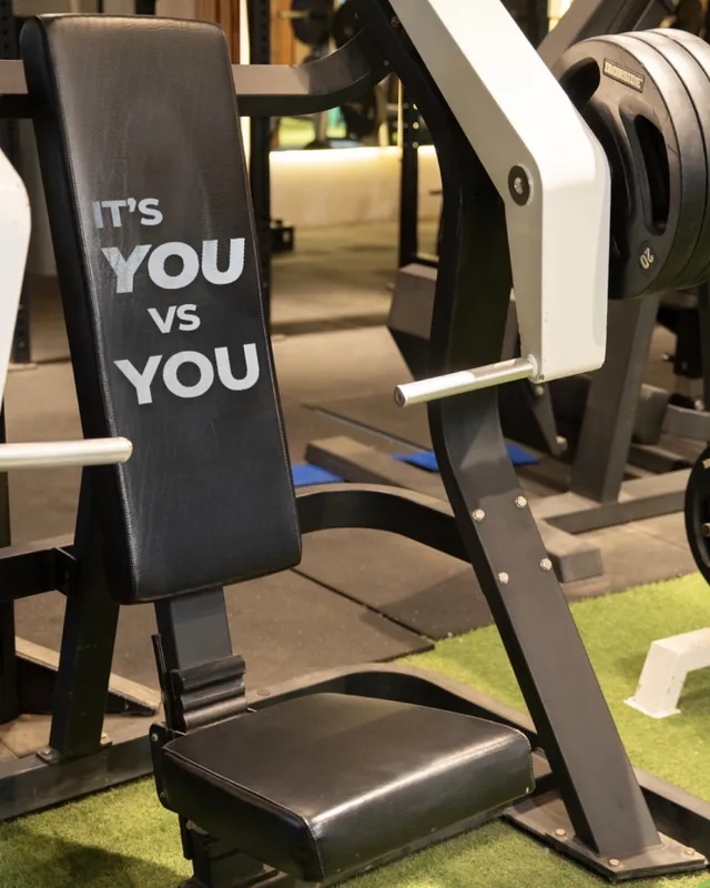Máquina de pecho con el respaldo «It's you vs you» en la sala de máquinas